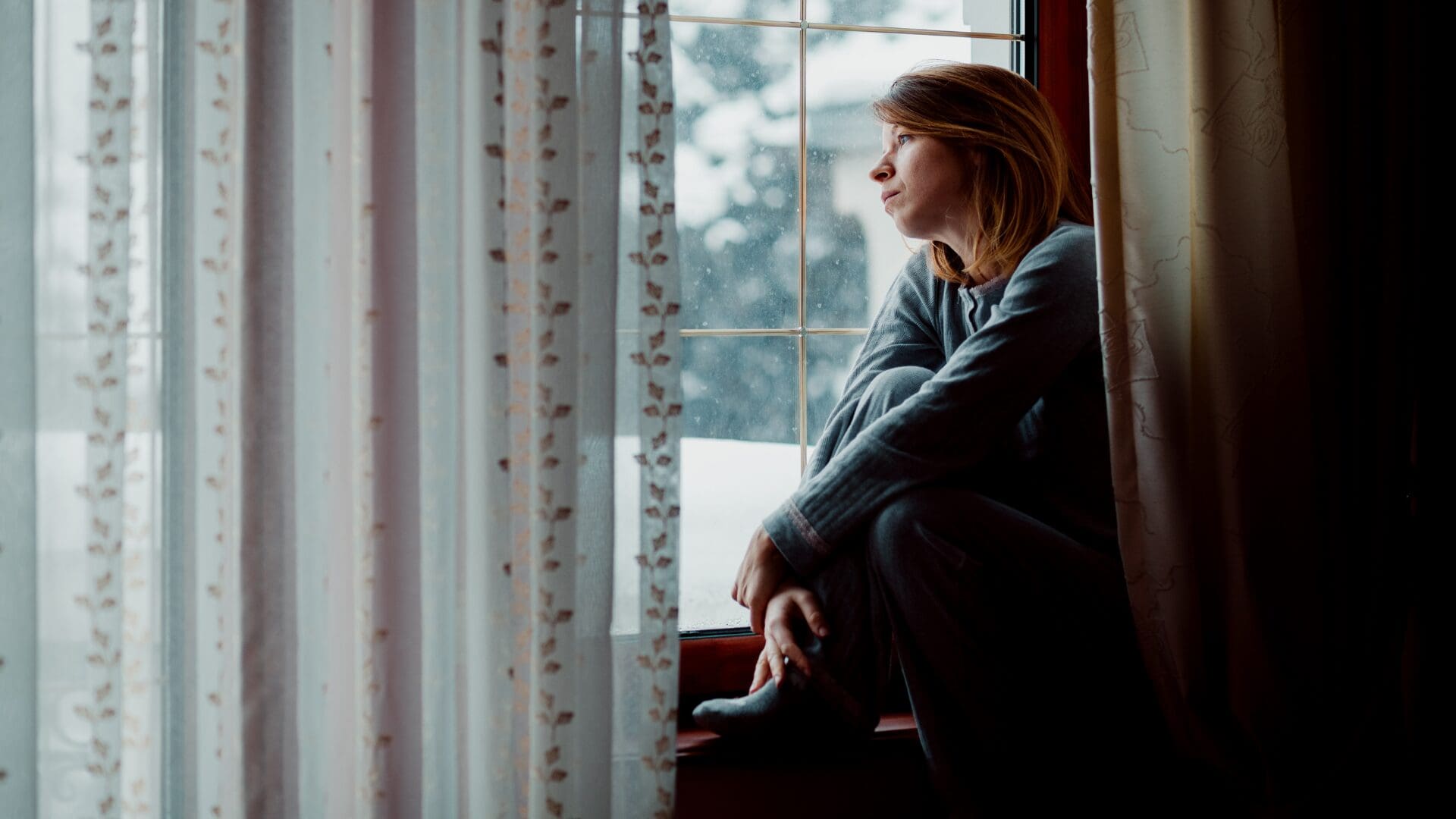 Woman sitting alone looking reflective, representing the quiet exhaustion of codependency and overfunctioning in relationships