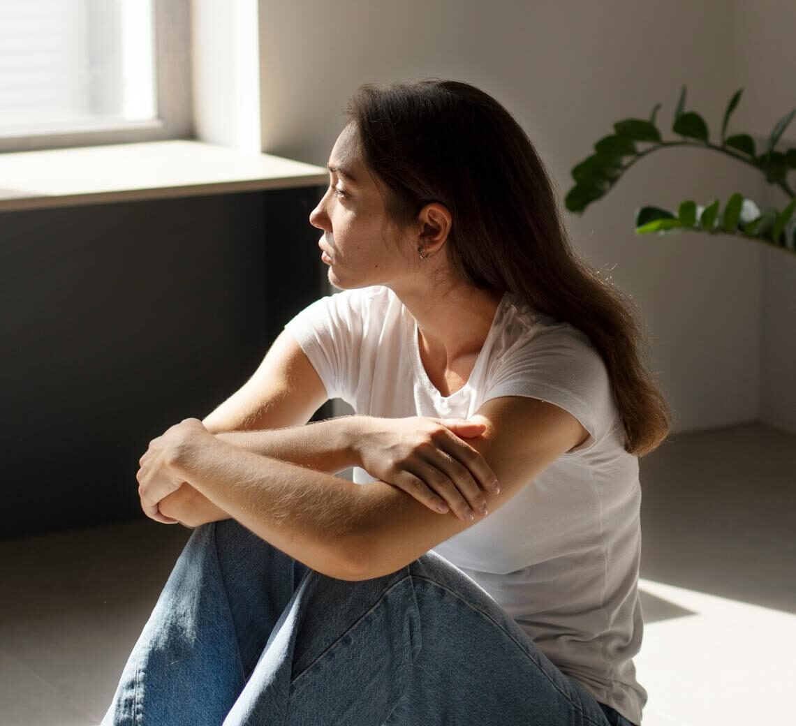 Woman sitting in quiet reflection representing emotional disconnection and the journey to reconnect with feelings in therapy